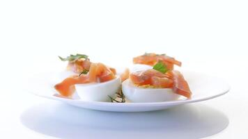 halves of boiled eggs with pieces of salted salmon isolated on white background video