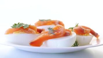 halves of boiled eggs with pieces of salted salmon isolated on white background video