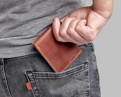 Man inserting personalized leather wallet with embossed initials into pocket photo