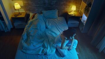 Top view of young woman suffering from insomnia while her husband is sleeping. Room with moon light. video