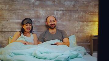 amusé couple en train de regarder la télé dans chambre avant Aller à sommeil video