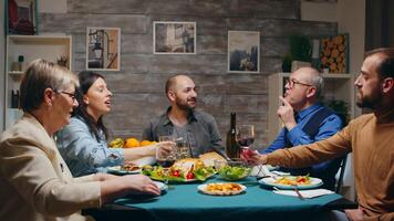 Friends at multigenerational family dinner late sunday night. Toasting with red wine. Slow motion shot video