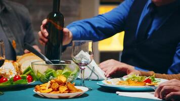 zoom in schot van jong Mens gieten rood wijn in een glas Bij familie diner. video