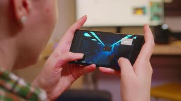 Back view of woman playing shooter games on smartphone. video