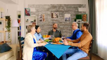 hermosa multigeneracional familia teniendo cena juntos con delicioso comida en acogedor y brillante habitación video