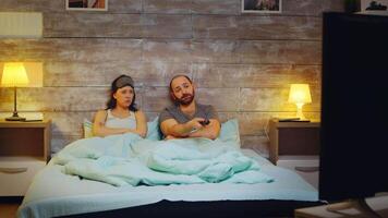 Kaukasisch paar in slaapkamer gebruik makend van TV afgelegen controle Bij nacht. video