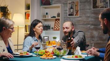 man gieten rood wijn naar haar mooi vrouw Bij multigenerationeel familie diner. video