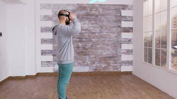 Designer in empty apartment arranging furniture using augmented reality. He puts the VR headset on while his colleague is talking with a real estate agent video