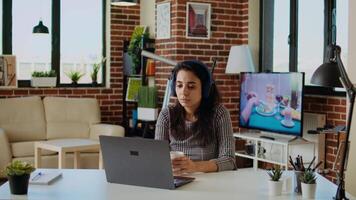 Teleworker checking emails on laptop while at computer desk, drinking coffee and listening music. Remote employee with headphones on working from home solving tasks, enjoying hot beverage, camera A video