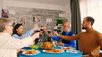 Young man clinking a glass of wine with his family while enjoying dinner. video