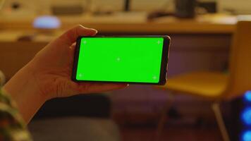 Back view of woman using smartphone with green screen mock-up video