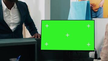 Afrikaanse Amerikaans arbeider toepassingen computer met groene scherm Scherm Aan Bij uitchecken balie, zetten kleren in een zak voor klant. werknemer looks Bij pc tonen copyspace mockup scherm. camera a. video