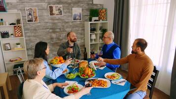 topp se av familj klirr glasögon med röd vin medan framställning en rostat bröd under middag med utsökt mat. video