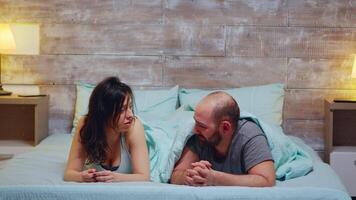jovem casal deitado dentro cama vestindo pijamas tendo uma conversação. video