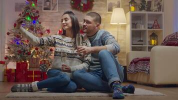 encantador Pareja en Navidad día Bebiendo champán hablando un selfie con teléfono inteligente video