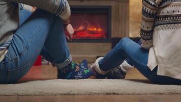 Young couple with warm socks in front of fireplace celebrating christmas. video