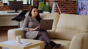 Telearbeiter Lügen auf Couch, entfernt durchführen Aufgaben im persönlich Büro, Fertigstellung Projekt. entspannt Freiberufler Eingabe Daten auf Laptop während Arbeiten von heim, Kamera b Schwenken Schuss video