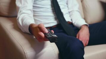 Businessman at home in formalwear and a tie resting and using tv remote control. video