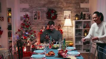 Teenage girl receiving a gift from her grandfather on christmas day. Traditional festive christmas dinner in multigenerational family. Enjoying xmas meal feast in decorated room. Big family reunion video