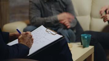 Close up of psychologist writing notes while couple yelling at relationship guidance. video