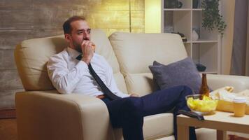 Hungry businessman having a conversation on his mobile phone while eating a burger. Beer on the table. video