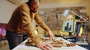 bem sucedido arquiteto falando em a telefone enquanto construção uma cidade modelo dentro dele casa escritório. video