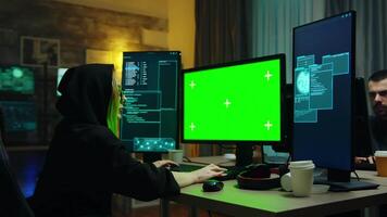 hacker niña vistiendo un negro capucha en frente de computadora con verde pantalla. identidad robando. video