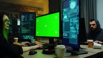 Zoom in shot of hacker girl in front of computer with green screen. Cyber criminal with hoodie. video