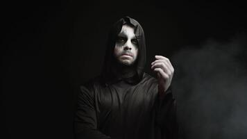 Man dressed up like grim reaper for halloween party over a black background with smoke video