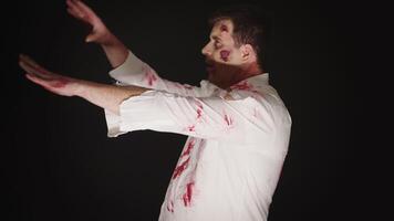 Guy dressed up like a zombie for halloween with blood and scars over black background. video