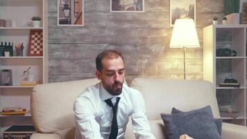 Businessman in formal wear sitting on couch eating chips while watching tv. video