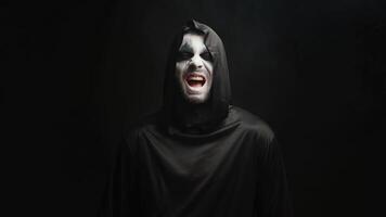 dyster skördeman med skrämmande skrattande över svart bakgrund. läskigt kostym. video