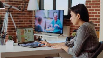 controlo remoto empregado otimizando mercado desempenho gráficos com televisão Como fundo ruído enquanto trabalhando a partir de casa dentro apartamento. teletrabalhador verificação conectados o negócio analytics estatístico dados Métricas, Câmera b video