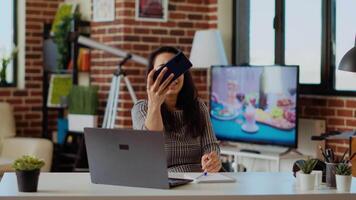 lachend gelukkig Indisch vrouw nemen selfie met mobiel telefoon terwijl glimlachen Bij huis kantoor bureau. persoon in mooi hoor elegant modern huis vastleggen foto gebruik makend van smartphone camera, camera b video