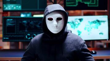 Zoom in shot cyber criminal wearing a white mask looking at the camera. video