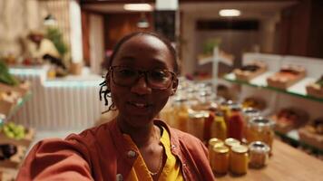 POV of african american buyer filming products at farmers market, promoting sustainable lifestyle and healthy nutrition with locally grown food. Woman recommending zero waste store. Handheld shot. video