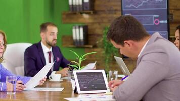 Successful businessman reading charts on his tablet. Businessman with his team in the conference room. video