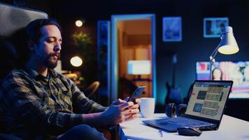 Man taking break from checking financial graphs on laptop, playing games on phone. Remote worker relaxing after analyzing business graphic figures, enjoying videogame on smartphone, camera B video