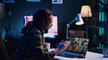 Remote worker greeting colleagues during business meeting on videocall in apartment office. Self employed man participating in remote videoconference telework call while at home, camera A video