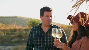 Couple clinking glasses with white wine in warm sunset light, slow motion footage video