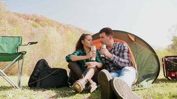 Couple enjoying a drink together in front of their camping tent. Camping chairs. Camping generator. video