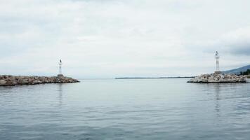 Drone flying over small lighthouses at the exit of the harbor. Beautiful sea with calm water. video