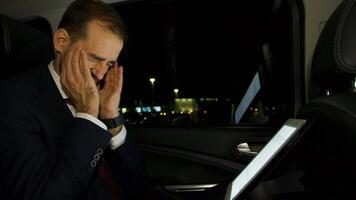 homme d'affaire travail à nuit sur le sien portable de le retour siège de le sien luxe voiture avec personnel conducteur. video