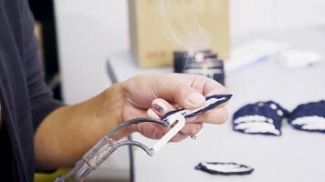 Female worker using a hot tool for edge badges in a sweing factory. Sewing production. video