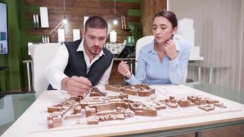 jovem masculino e fêmea arquiteto trabalhando em uma miniatura cidade. video