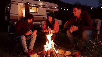 kaukasisch freunde genießen zusammen ein Flasche von Bär um Camping Feuer. retro Wohnmobil Lieferwagen. video