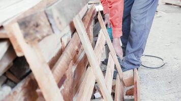 Mens gebruik makend van elektrisch zag naar besnoeiing houten pallets in een ware huis. video