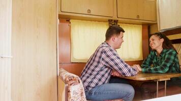 Couple laughing together and holding hands inside of retro camper van. Cheerful couple. video