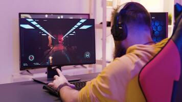 Over the shoulder footage of man playing professional video games in a room with colorful neon lights.