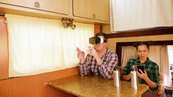 Young man with vr goggles inside of retro camper van. Woman using phone inside retro camper van. video